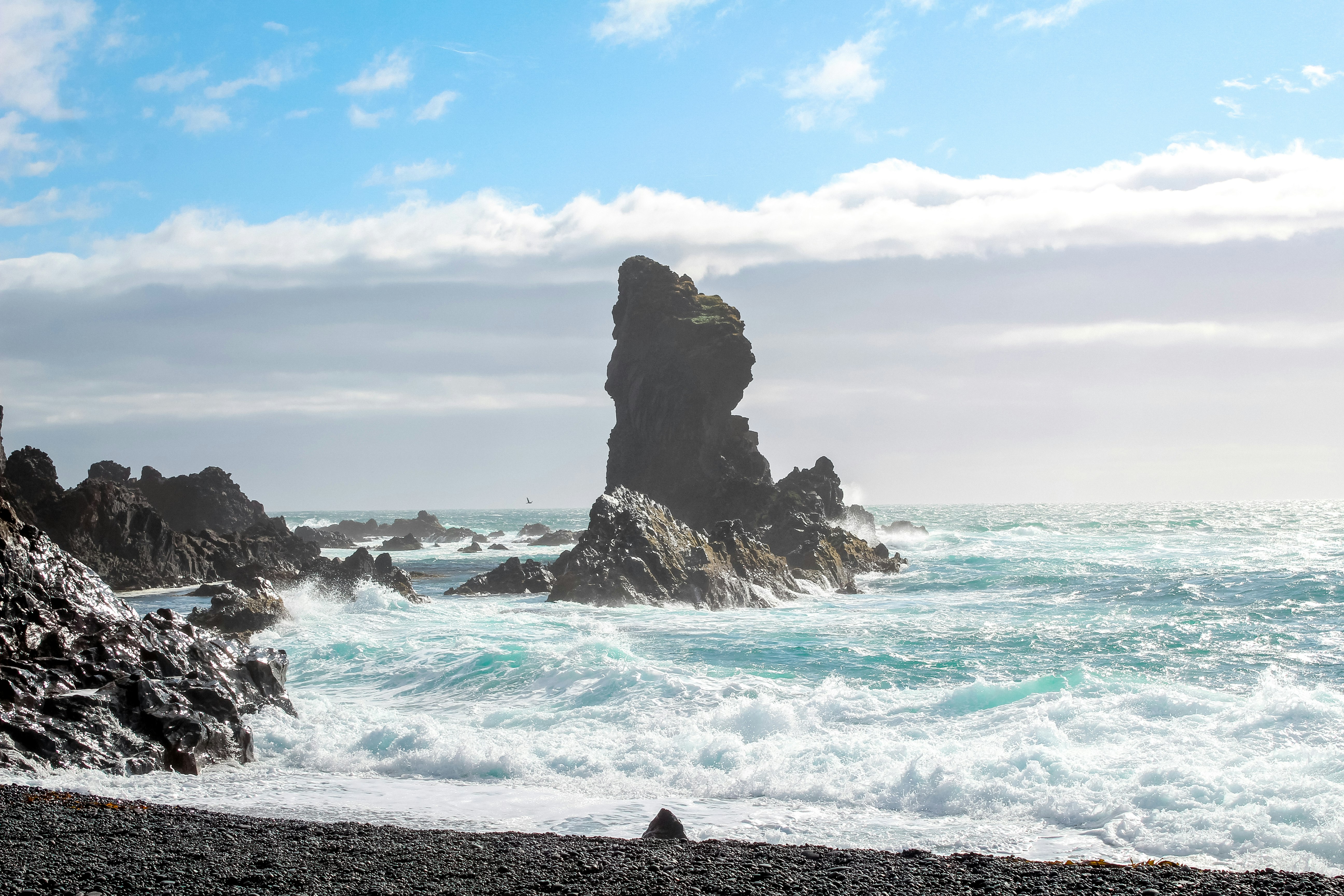 brown rock formation on sea under blue sky during daytime